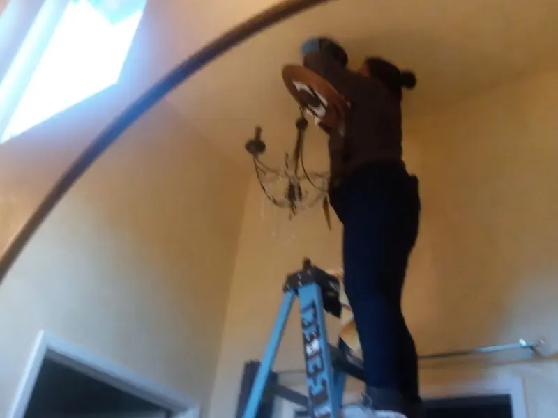 Electrician installing a chandelier in a Blanchester residence